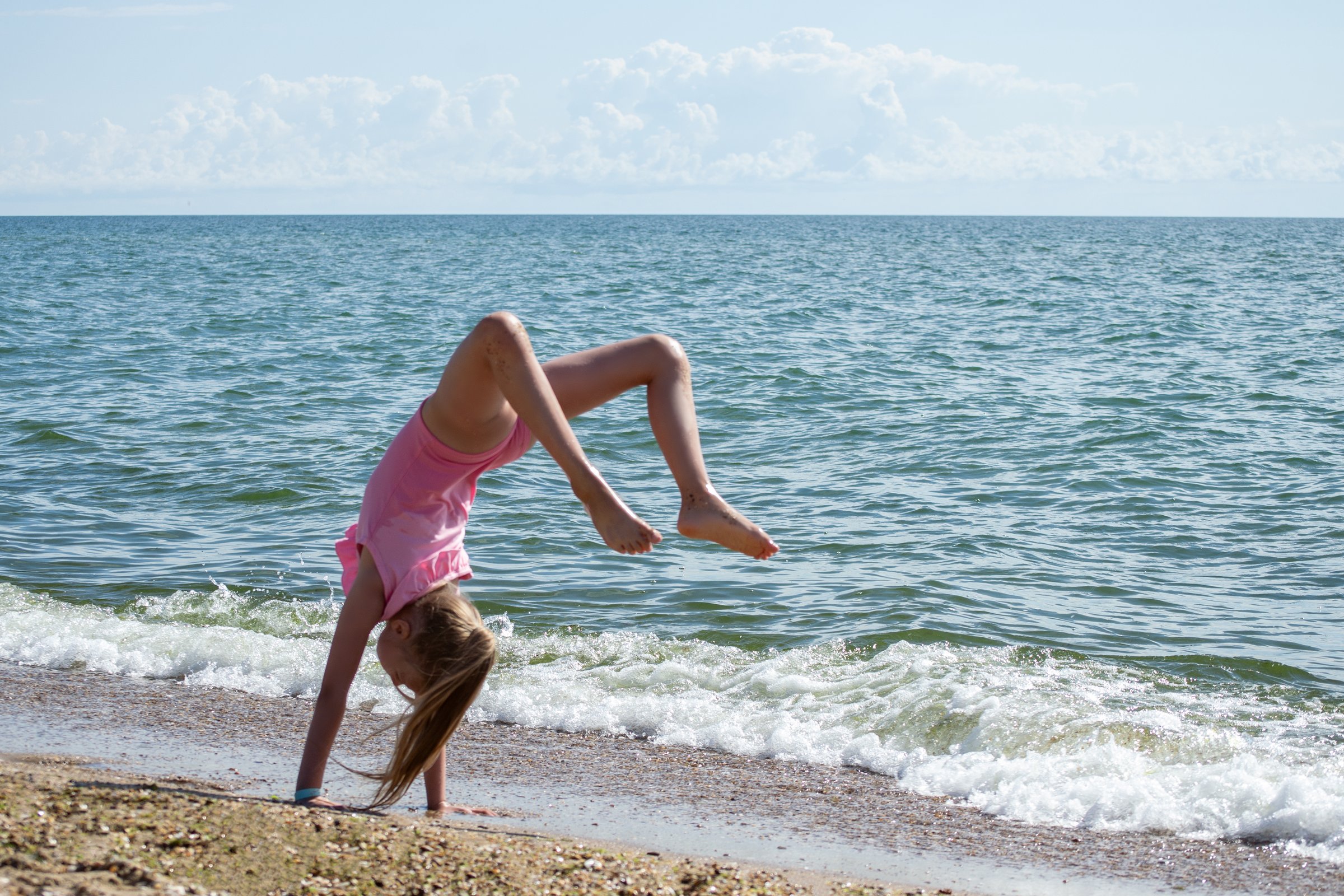 A girl gymnast trains on the seashore
