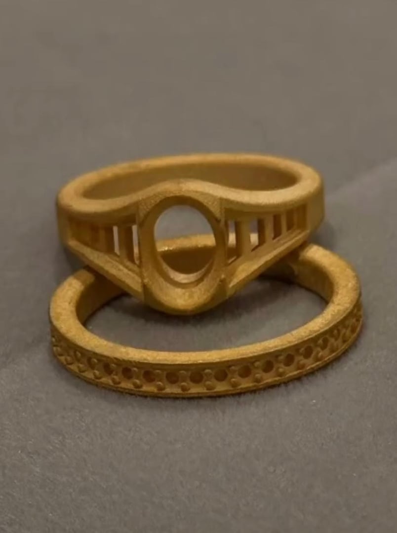 Two wooden rings with intricate cutout designs on a gray surface, one stacked on top of the other.