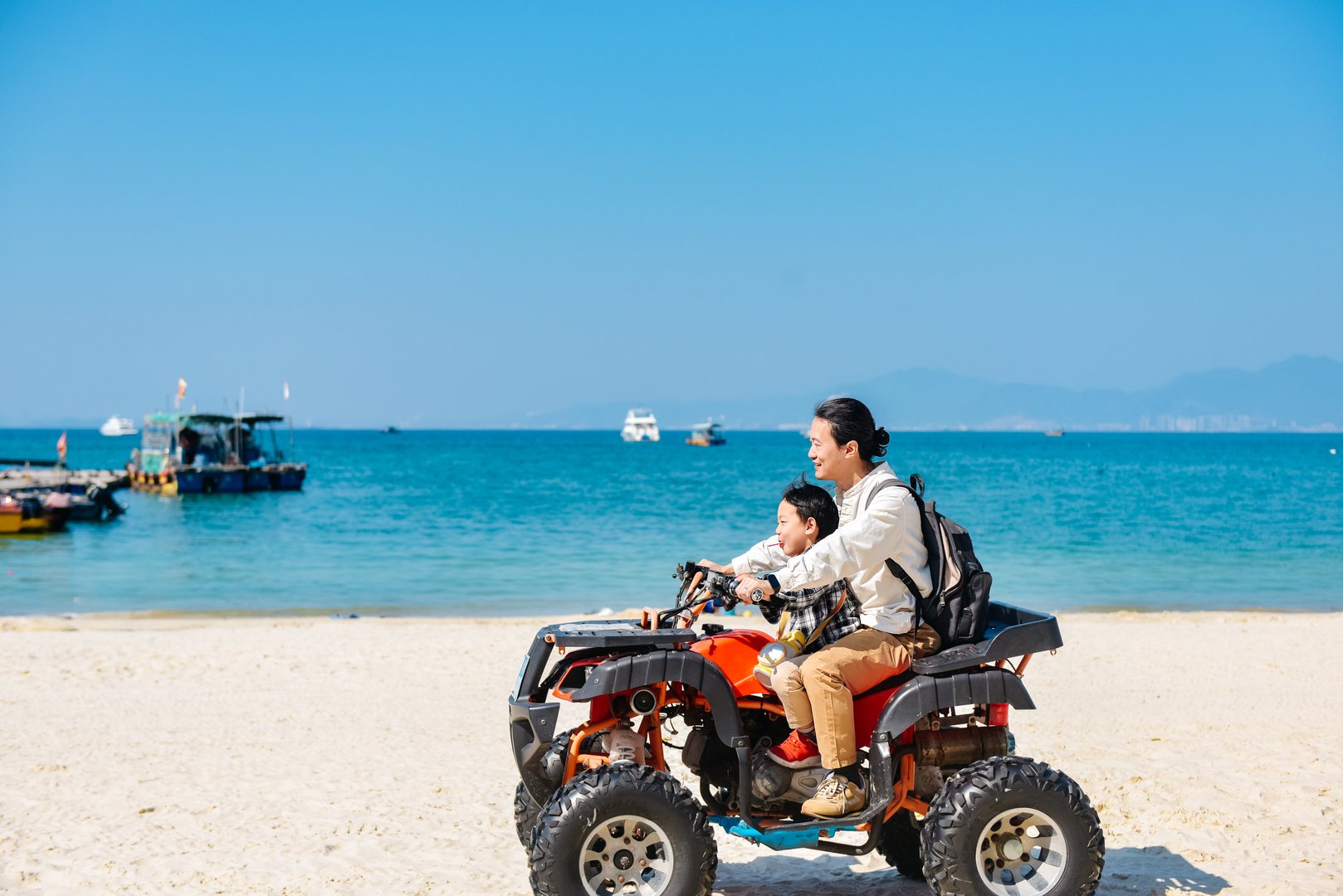Asian kid and dad riding ATV at in Xunliao Bay, Huizhou city, Guangdong Province, China, during January