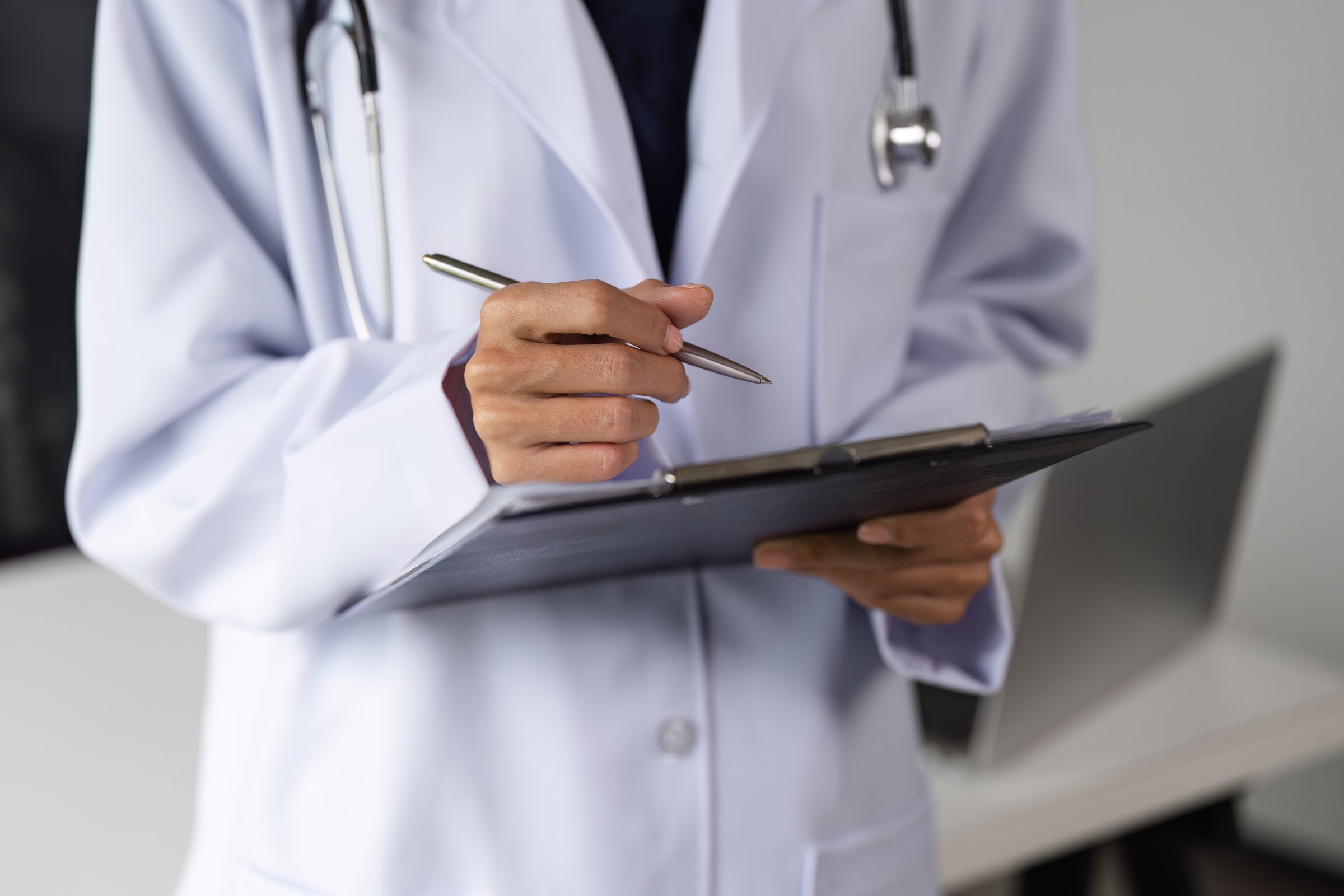 Confident female doctor in a clinic, holding a clipboard, ready to assist patients with professional care.