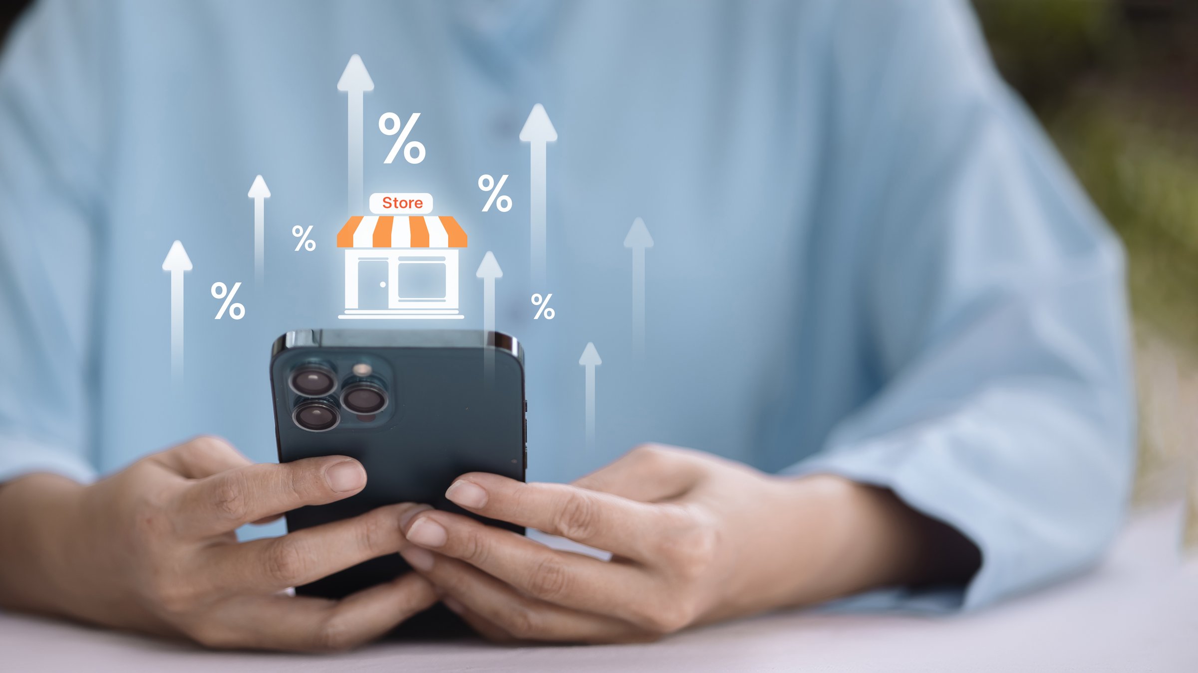 Close-up of hands holding smartphone with digital store icon and percentage growth. Concept of online shopping, e-commerce business, mobile retail, and digital marketing sales increase.