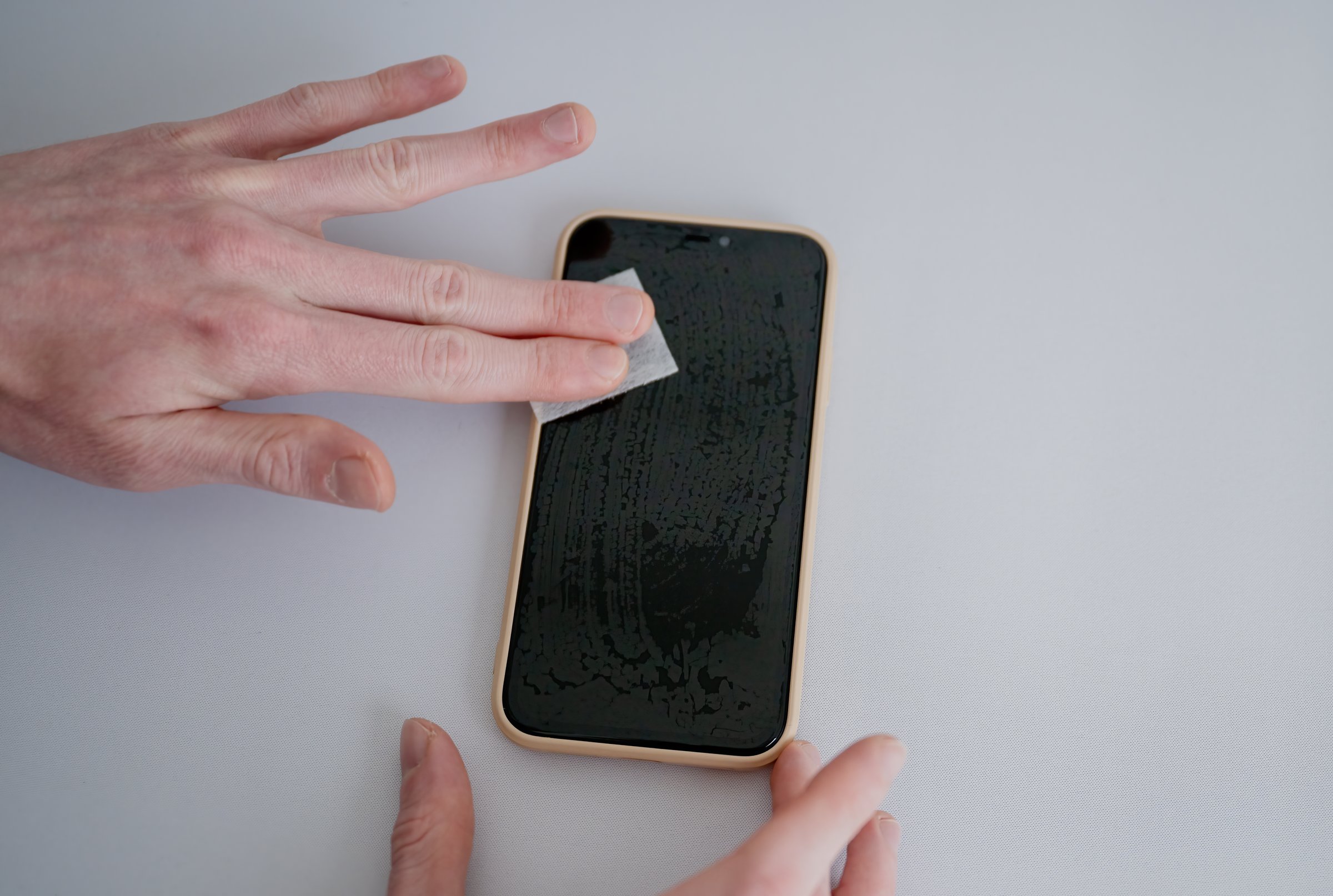 Man cleaning smartphone screen with dry wipe before applying screen protector