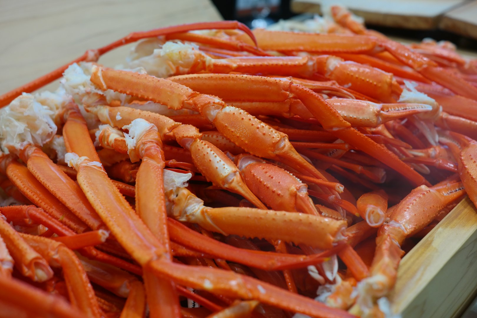 Boiled crab legs in a wooden box on a wooden table.