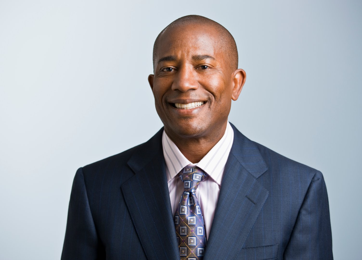 Attractive African American headshot dressed in a suit and tie, facing the camera. Horizontal