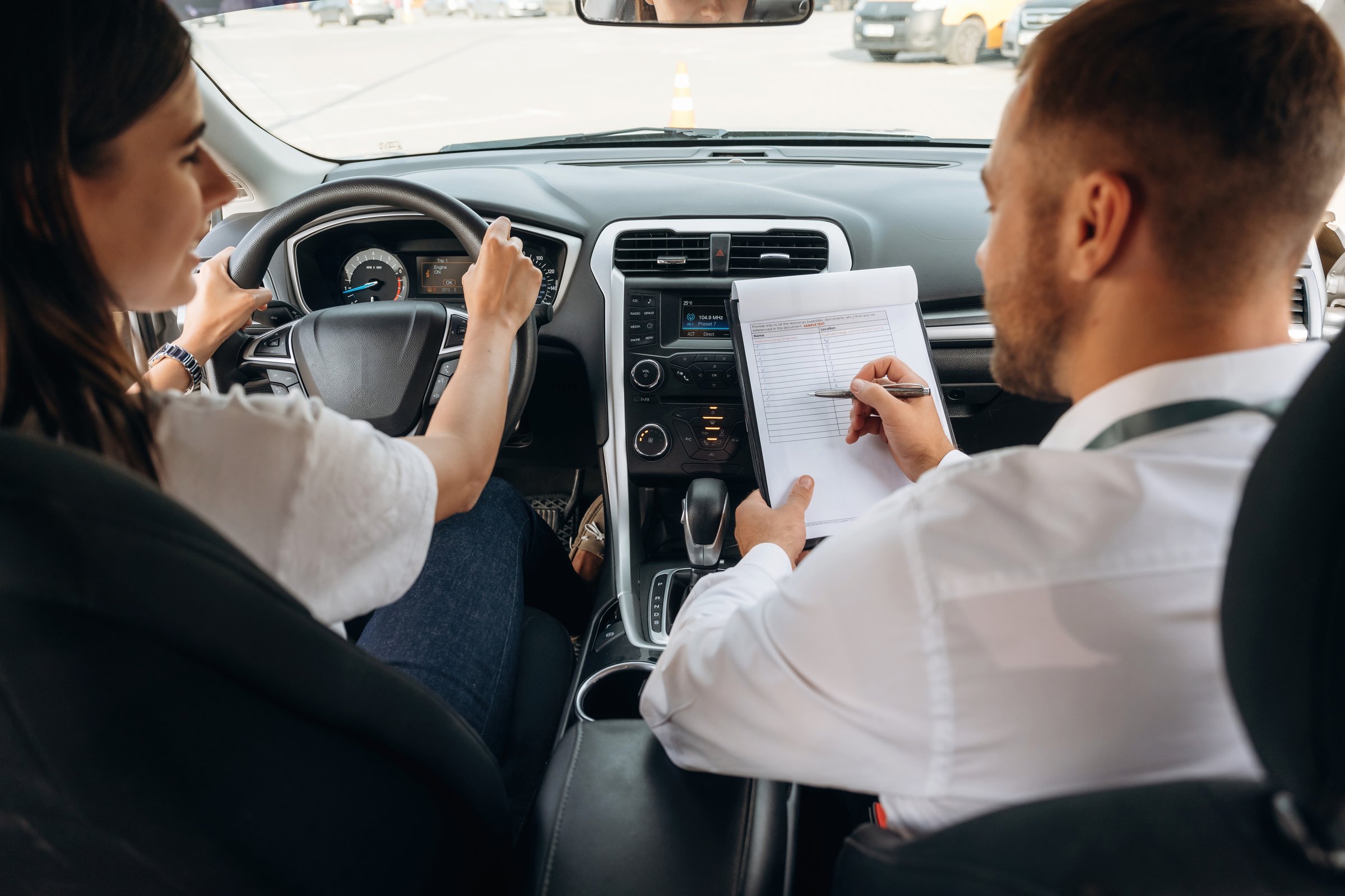Woman is with instructor in car, driving school concept.