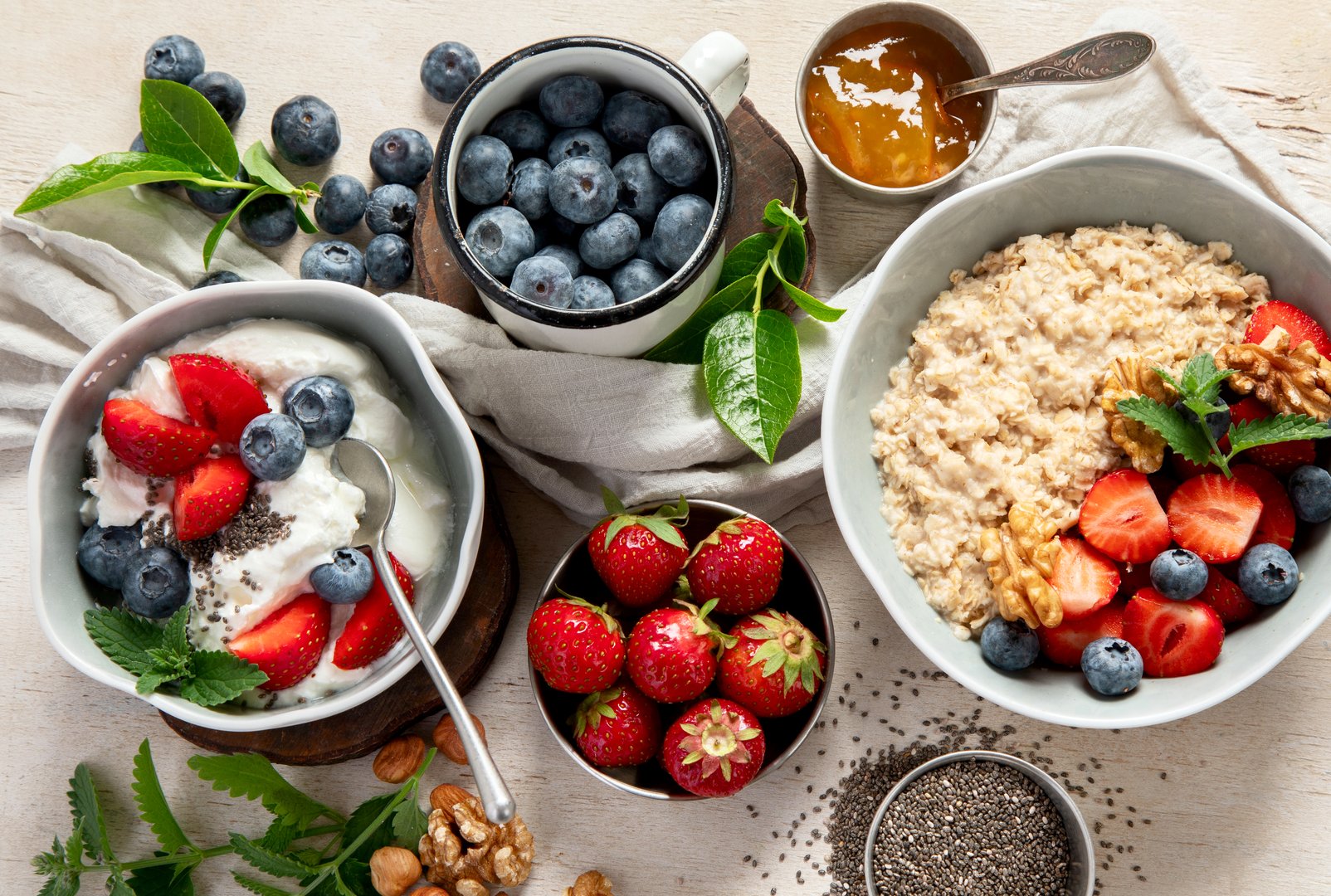Organic ingredients for healthy breakfast -  yoghurt, nuts, fresh fruits, oatmeal, whole grain flakes on white background. Top view.