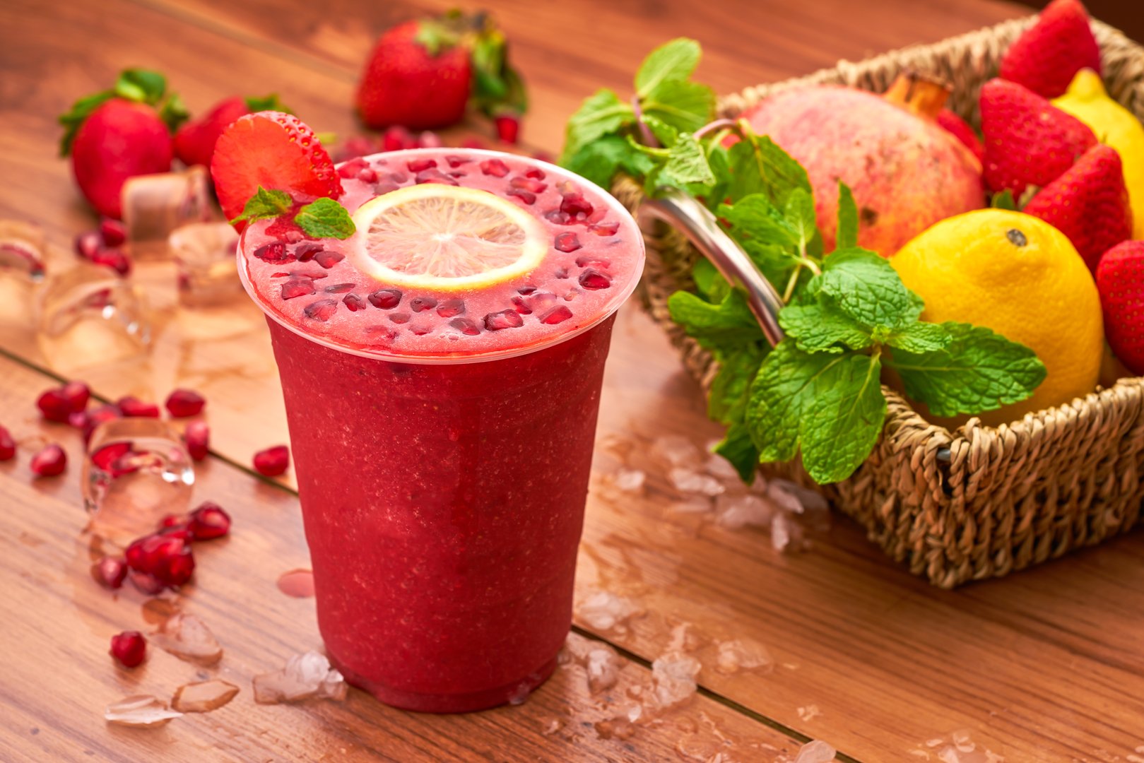 Pomegranate and Strawberry Smoothie with Lemon, Mint, and Fresh Fruit in glass side view of delicious refreshment