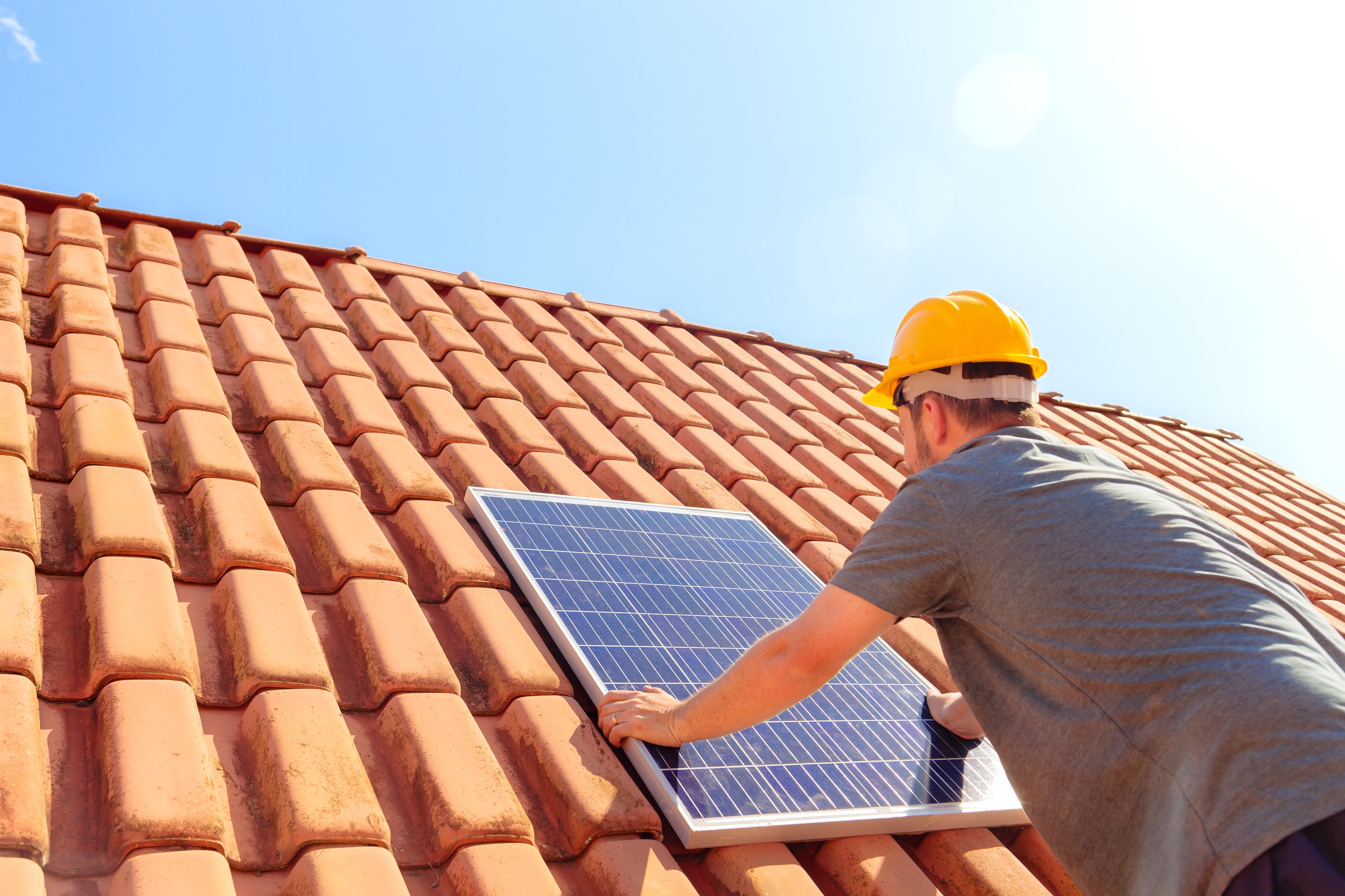 Technician installing a solar panel on a house roof, showcasing renewable energy solutions and sustainable living. Ideal for companies promoting clean energy and solar power installations