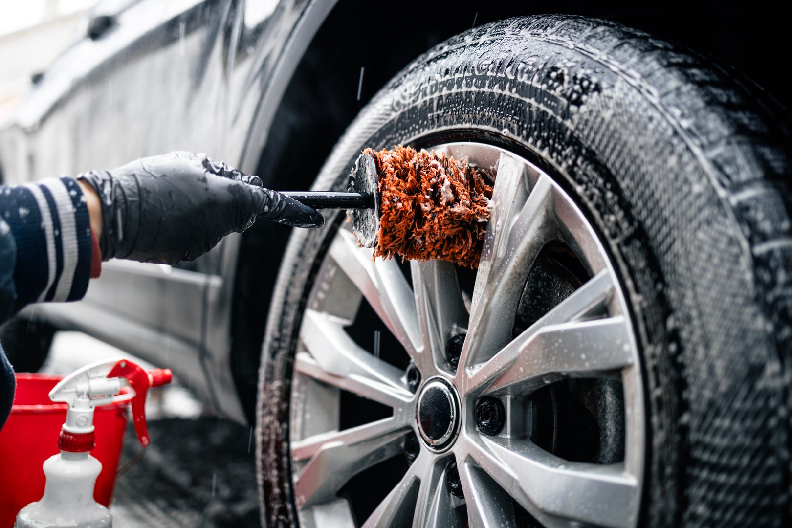 Close up view of car wheel being washed with the brush and soap.