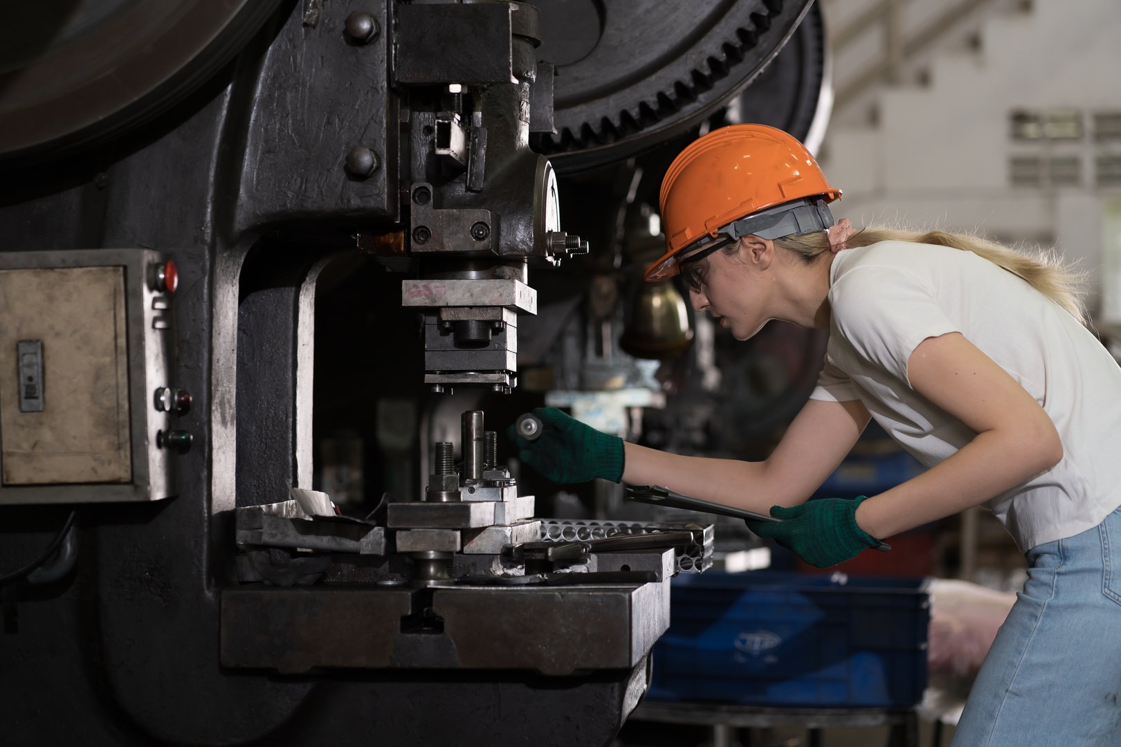 Woman worker, factory and machine. Female worker working with automated lathe machine in the industry factory. Factory woman, safety helmet, factory in industry production
