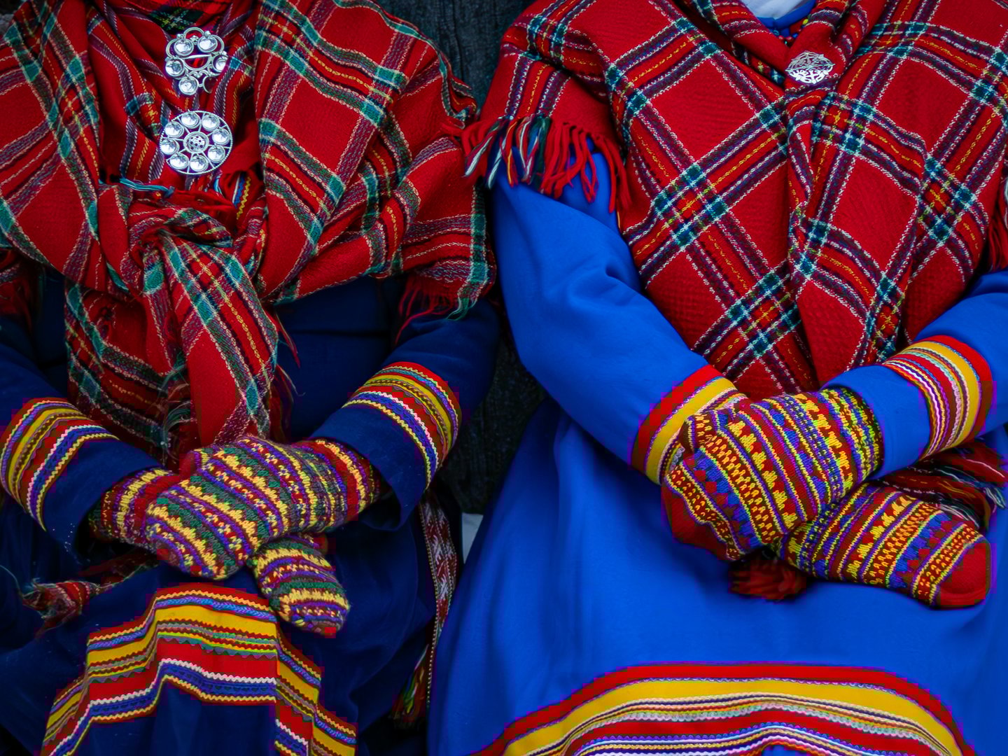 Two Sámi women in traditional clothing. Kolt, handmade mittens, risku and shawl.