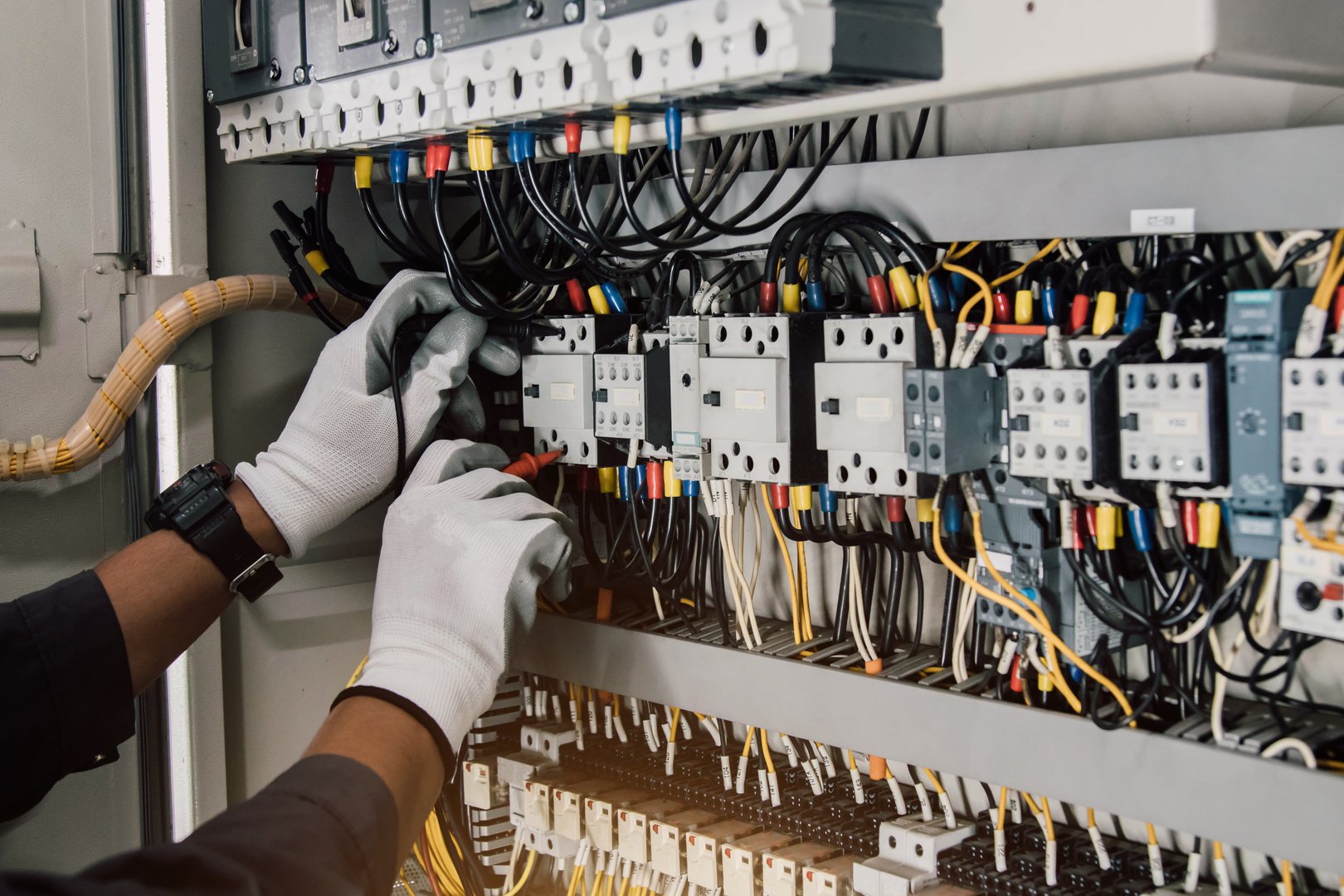 Electrician engineer tests electrical installations and wires on relay protection system.