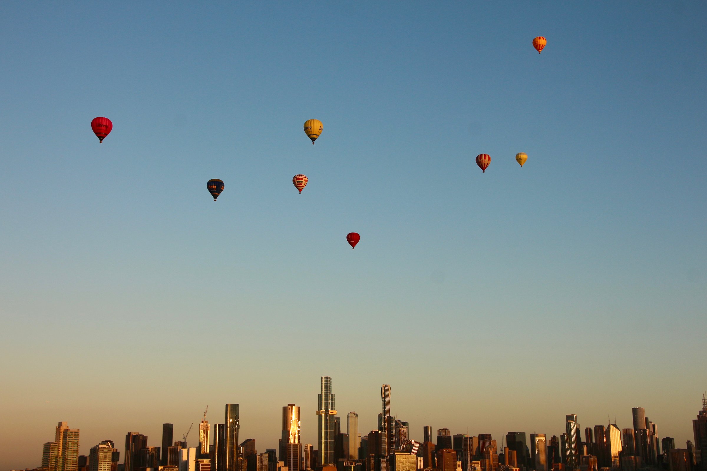 Dawn sunrise in Melbourne with eight hot air balloons over the city skyline and the  morning sky