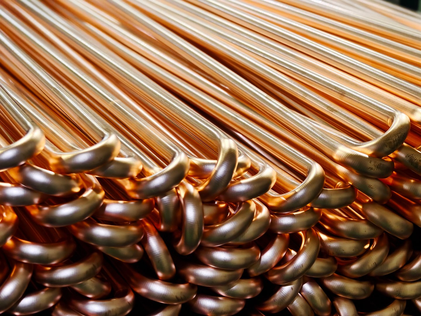 Close-up view of neatly stacked copper pipes in a manufacturing facility, showcasing their shine and smooth texture, ideal for industrial and plumbing applications.