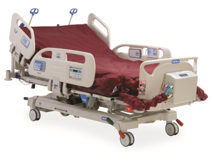 A hospital bed with electronic controls and side rails, featuring a maroon mattress cover and various monitoring equipment.