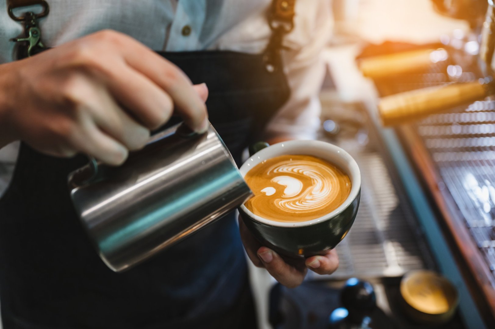 barista making latte art, shot focus in cup of milk and coffee, vintage filter image