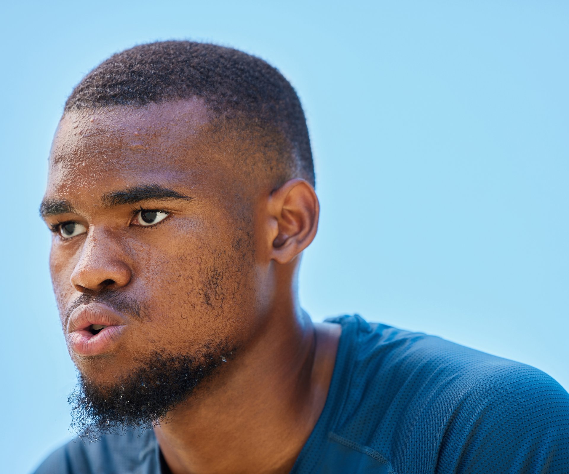 Face, sports fitness and black man in nature ready for workout, exercise or training. Basketball, blue sky or serious male athlete from Nigeria with vision, focus or thinking about goals outdoors.