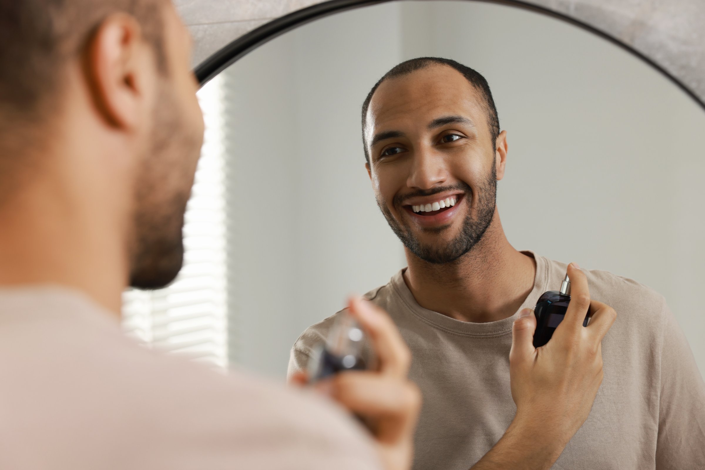 Smiling man looking in mirror after grooming