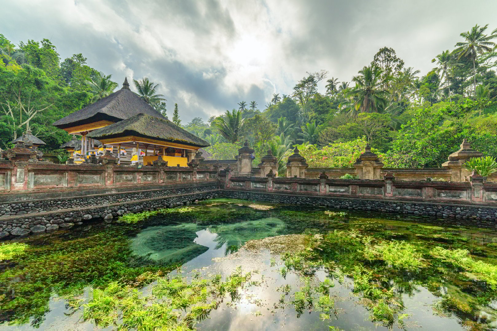 Awesome view of the pond at Tirta Empul Temple in Bali, Indonesia. The holy spring water arises from the ground. The Hindu Balinese water temple is a popular tourist attraction of Asia.