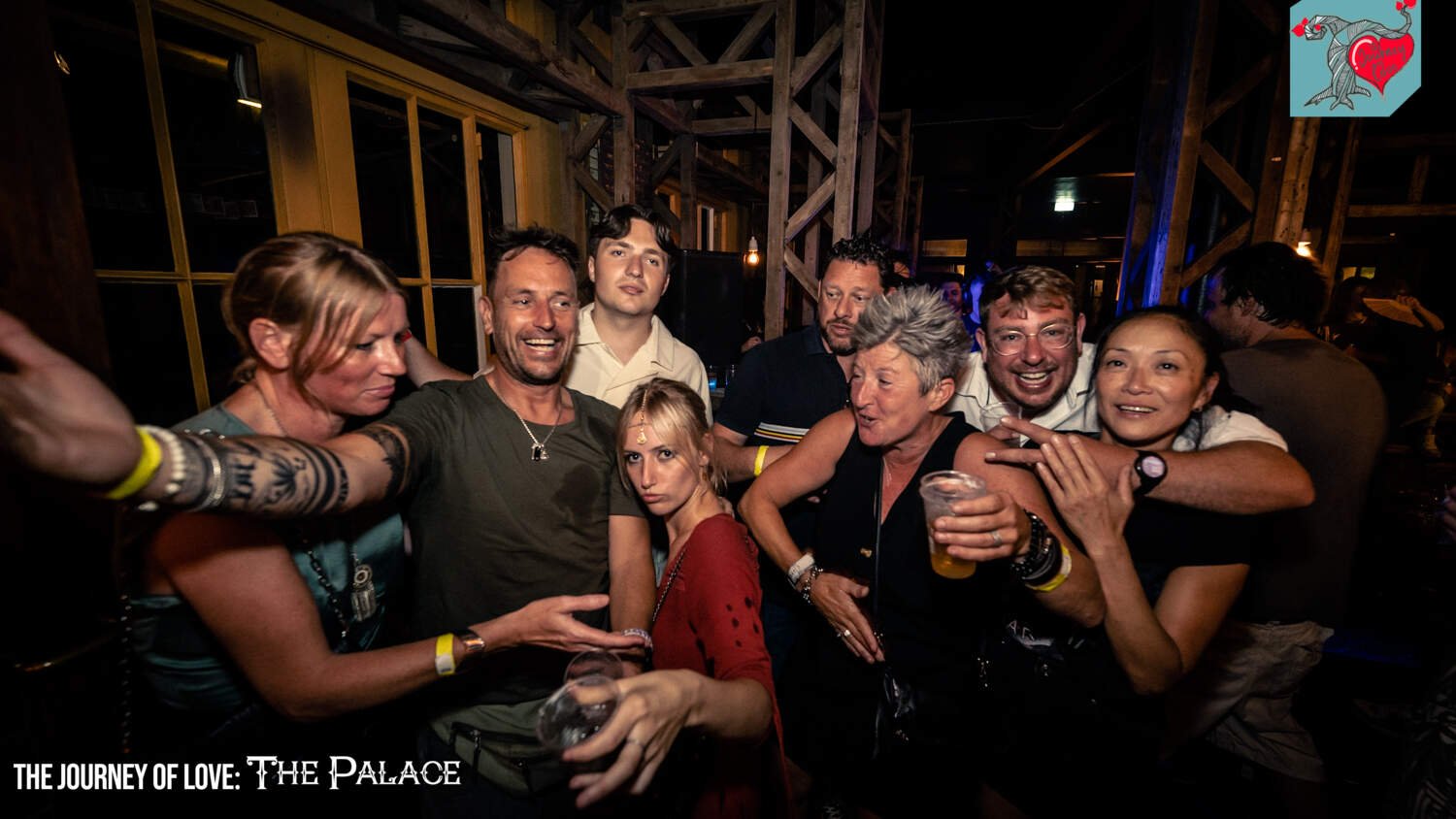 Group of people enjoying a lively nightlife gathering with drinks and smiles in a dimly lit venue.