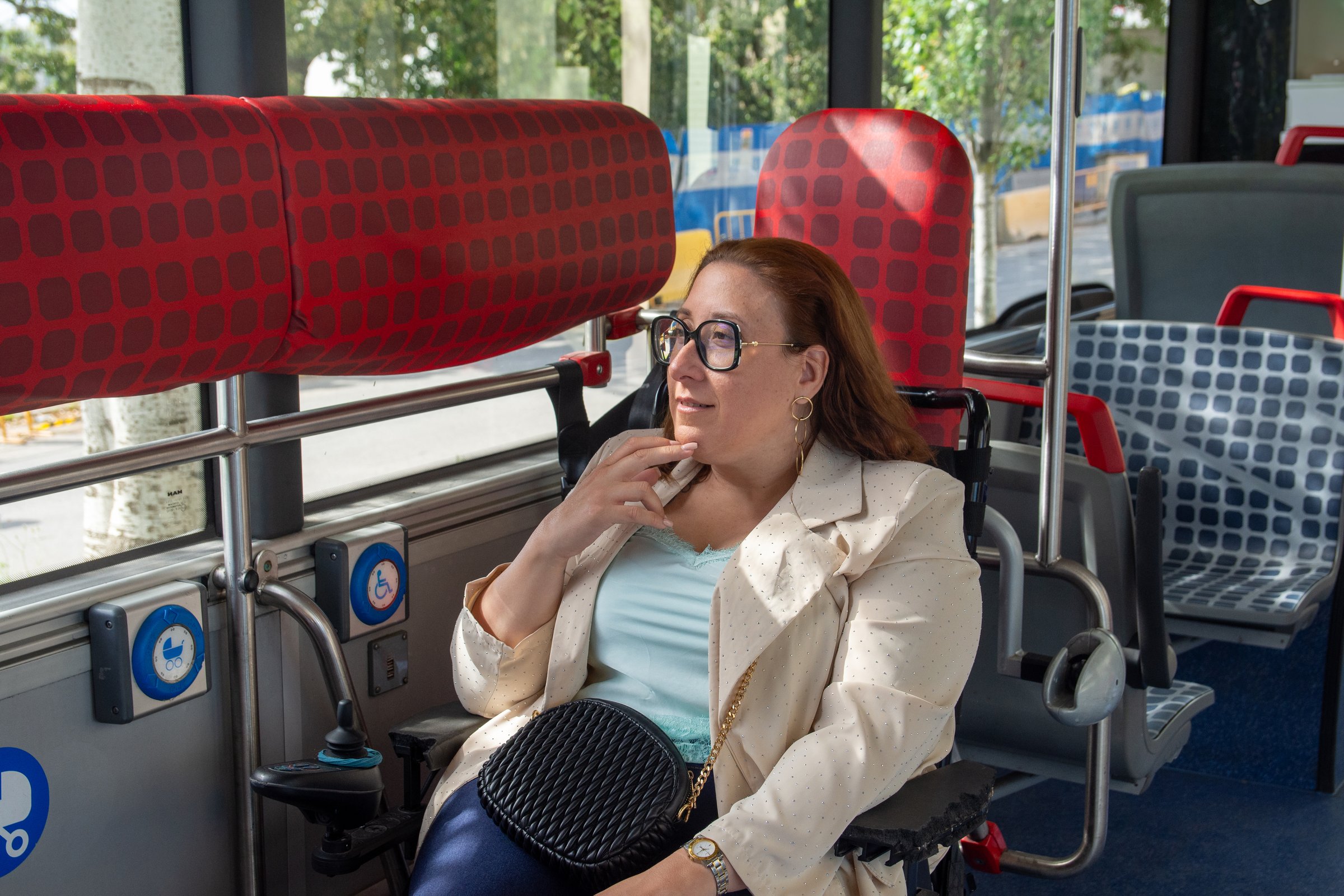 Woman using wheelchair is traveling by bus, looking out the window and enjoying the ride in the city. Concept of inclusion, adapted public transport
