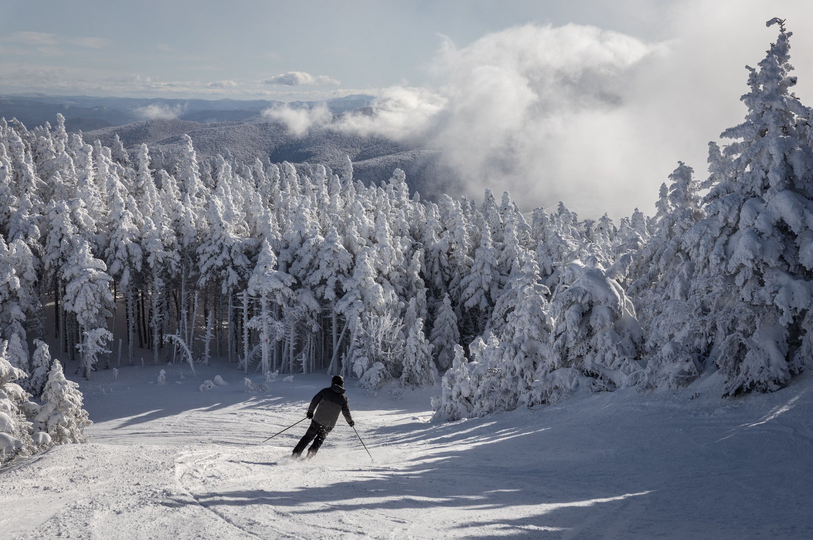 A skier descends a snowy slope surrounded by frosted trees. Green Mountains of Vermont