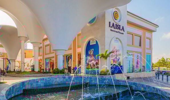 La Isla Shopping Village entrance with fountains, arched white structures, and colorful storefronts.