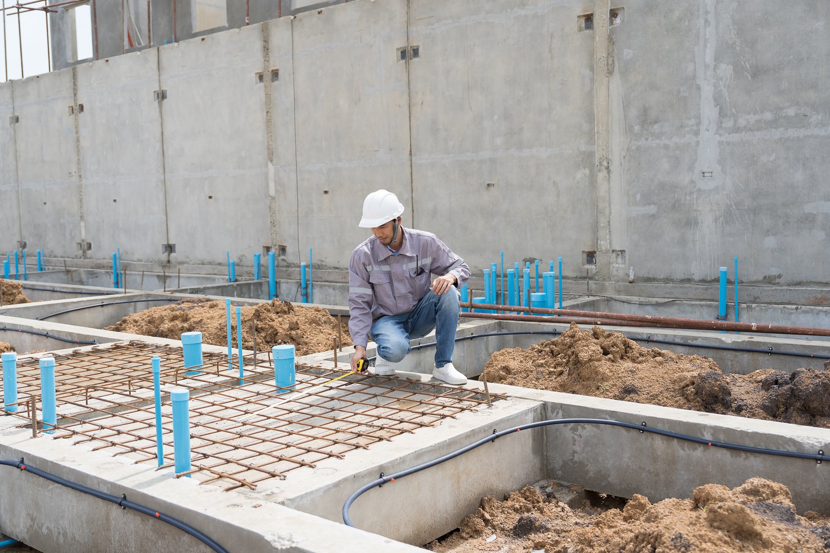 Construction site. Building foundation structure. Civil engineer. Network of pipes. Construction engineer supervising construction work at construction site. Plumber working in sewer pipes area