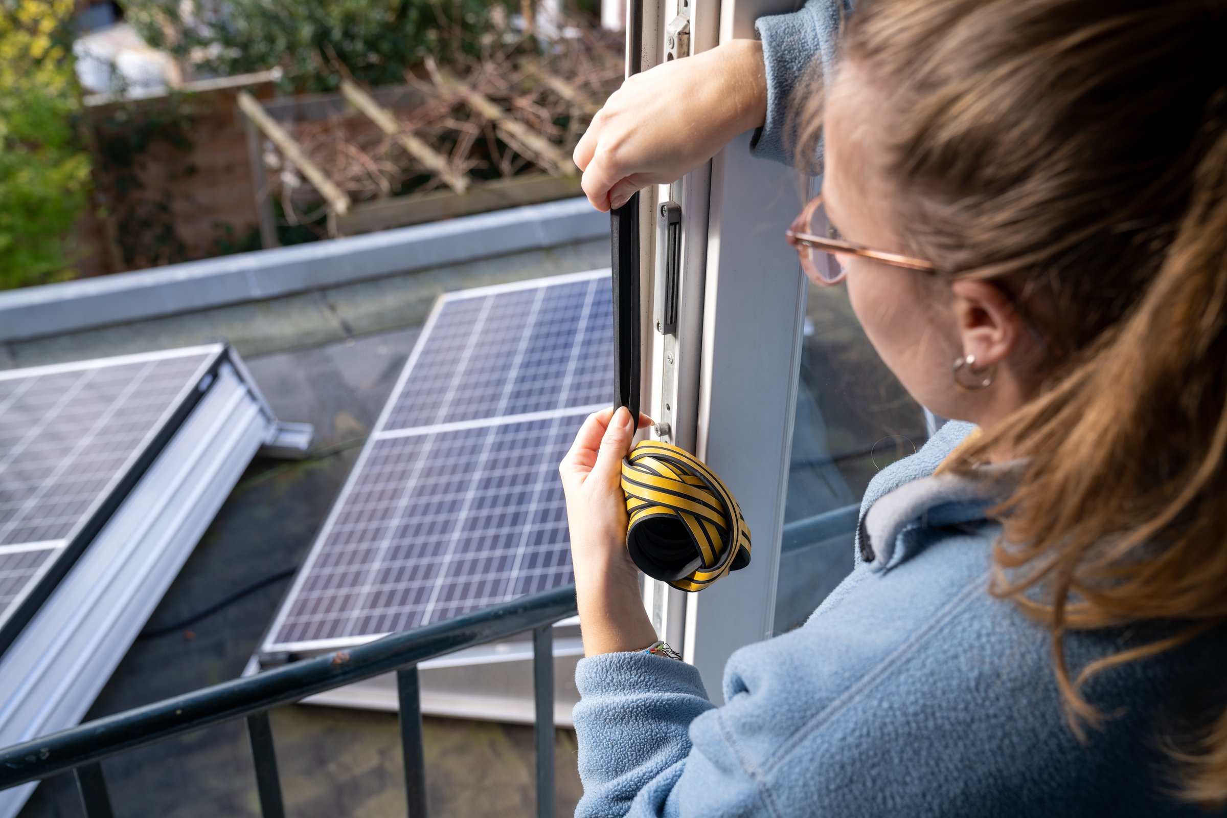 Young woman makes her home energy efficient with the help of draft strip and solar panels to save the planet.