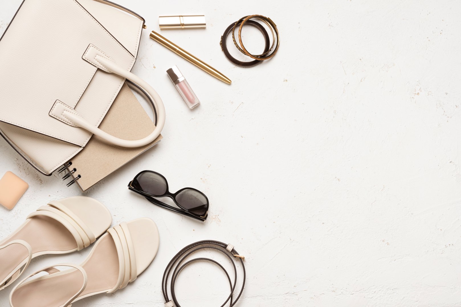 Female summer accessories and clothing items on light textured background with copy space