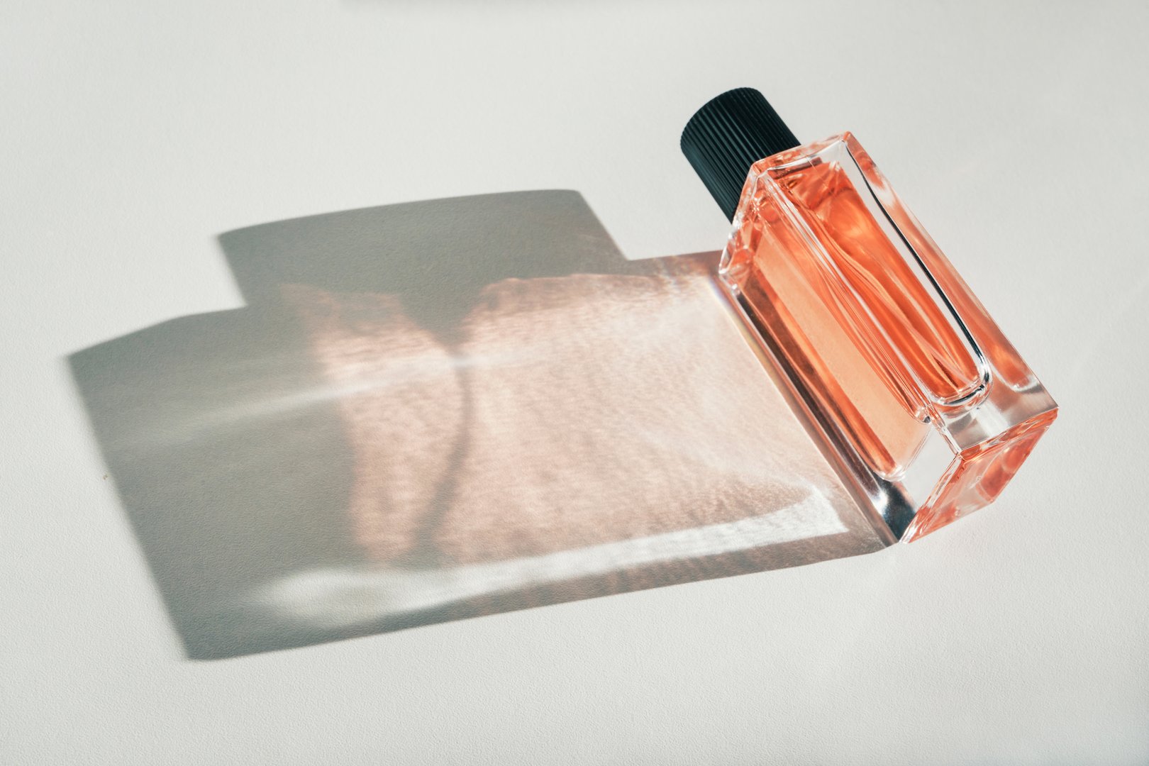 Perfume bottle presenting luxury fragrance with sunlit shadow and reflection