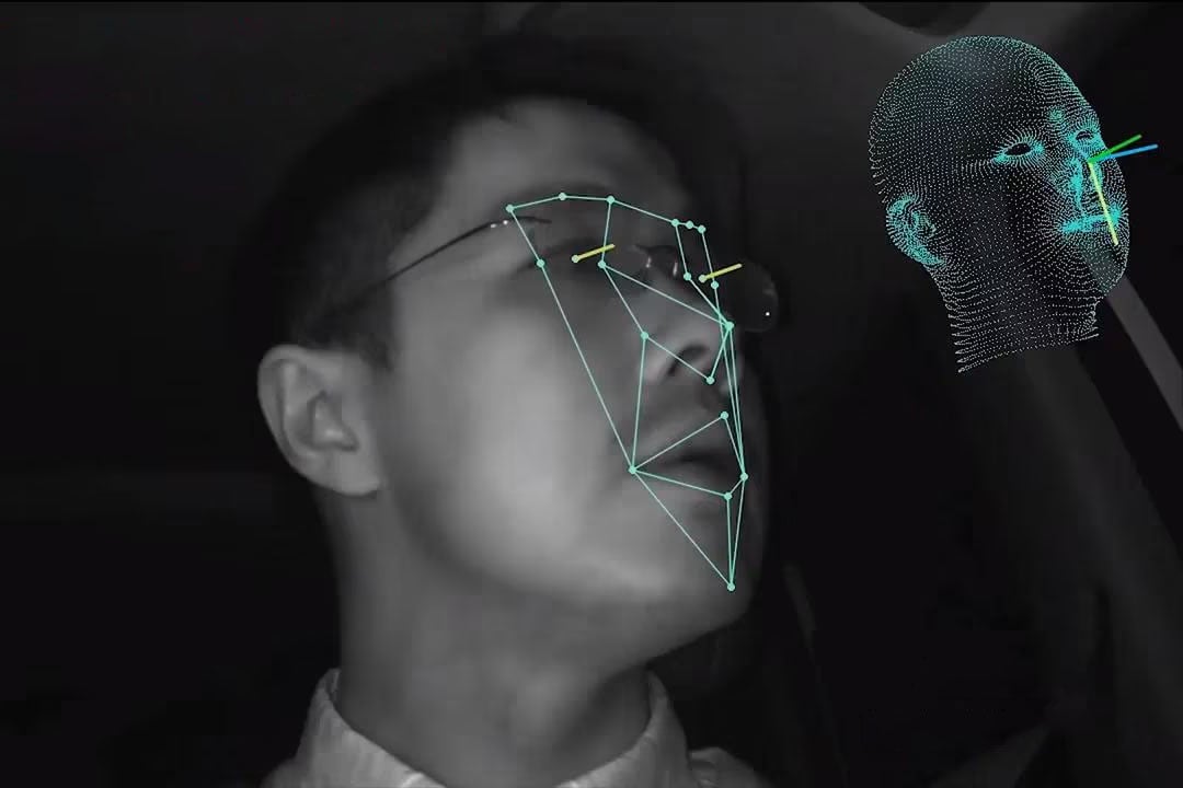 Person in a car with facial recognition overlay and a 3D face model. Green lines and points highlight facial features.