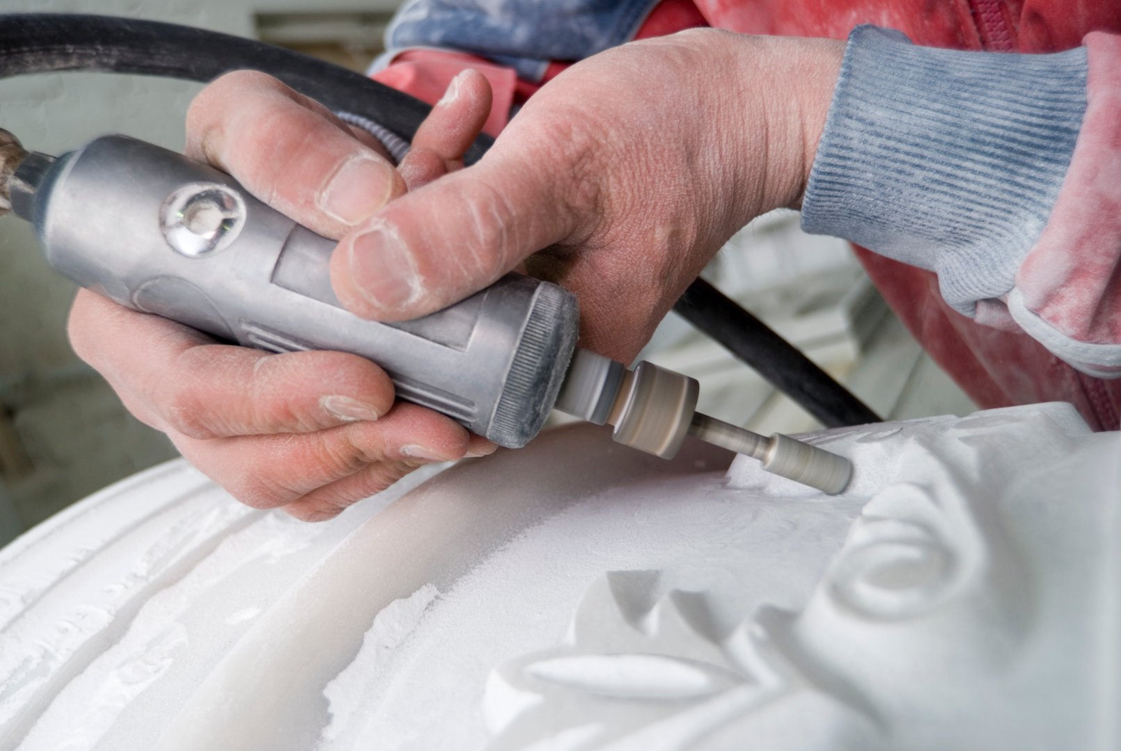 Close-up of a person using a rotary tool to carve intricate designs into a piece of stone.