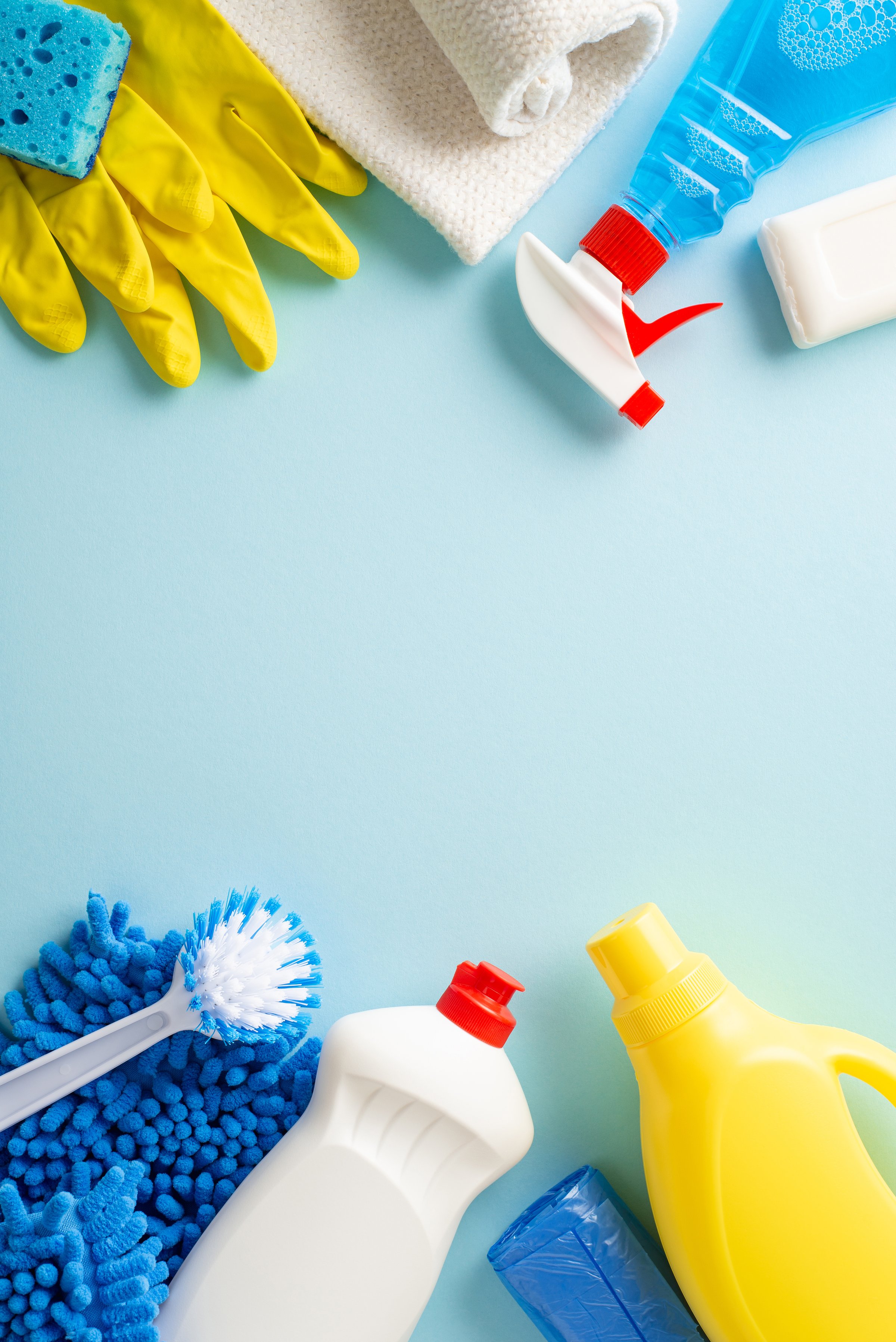 A clean sweep in aesthetics. Top view vertical photo featuring cleaning essentialsârags, gloves, and detergent bottlesâarranged on calming pastel blue background. Adaptable space for text or branding