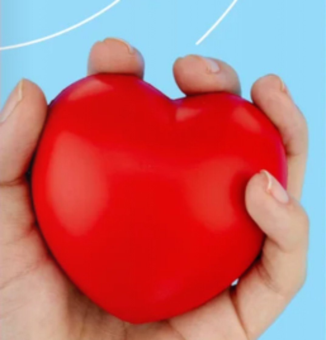 Hand holding a red heart-shaped object against a blue background.