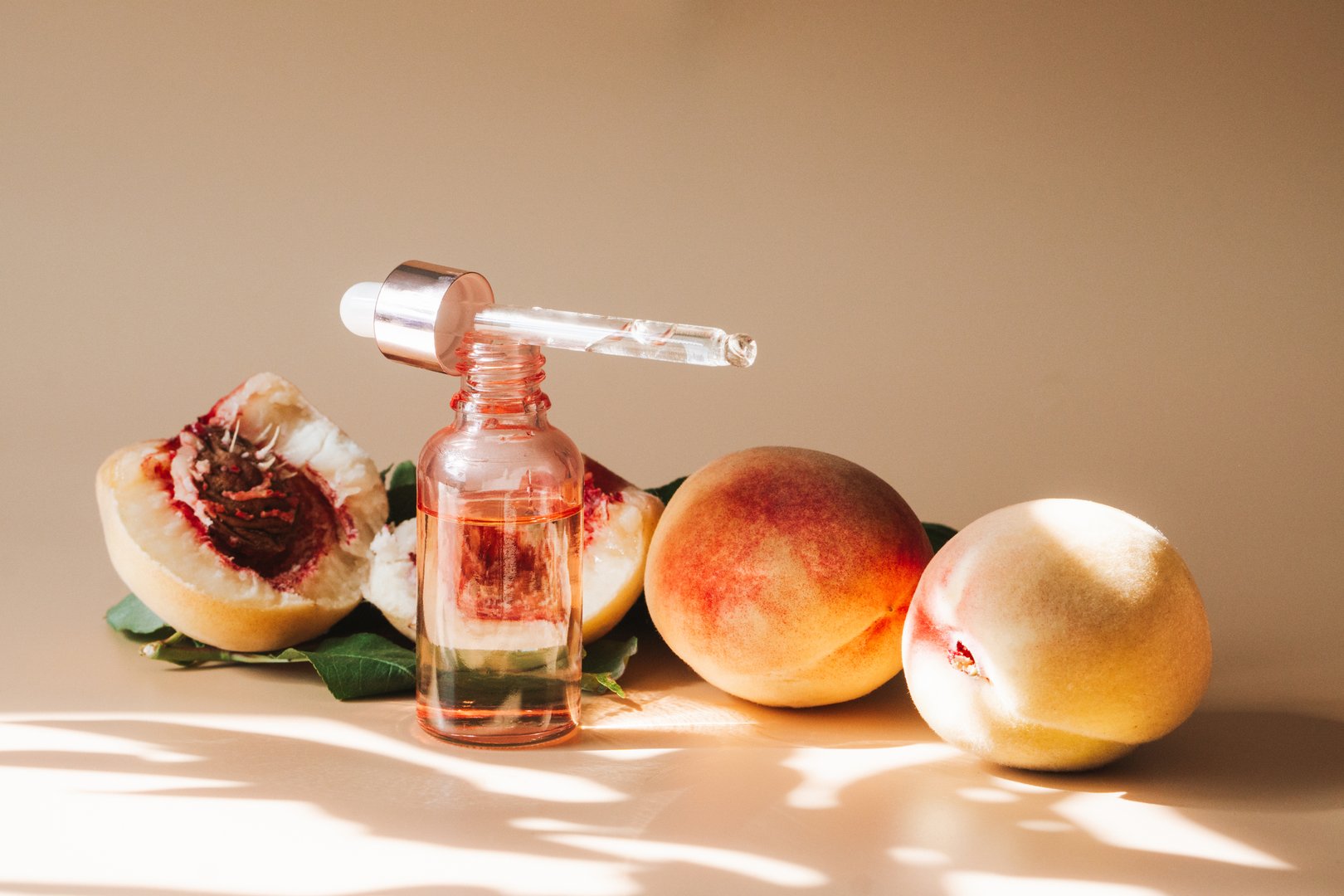 Natural cosmetics, hair and skin care. Natural peach oil. Bottle with essential peach oil and fresh peaches on beige background. High quality photo