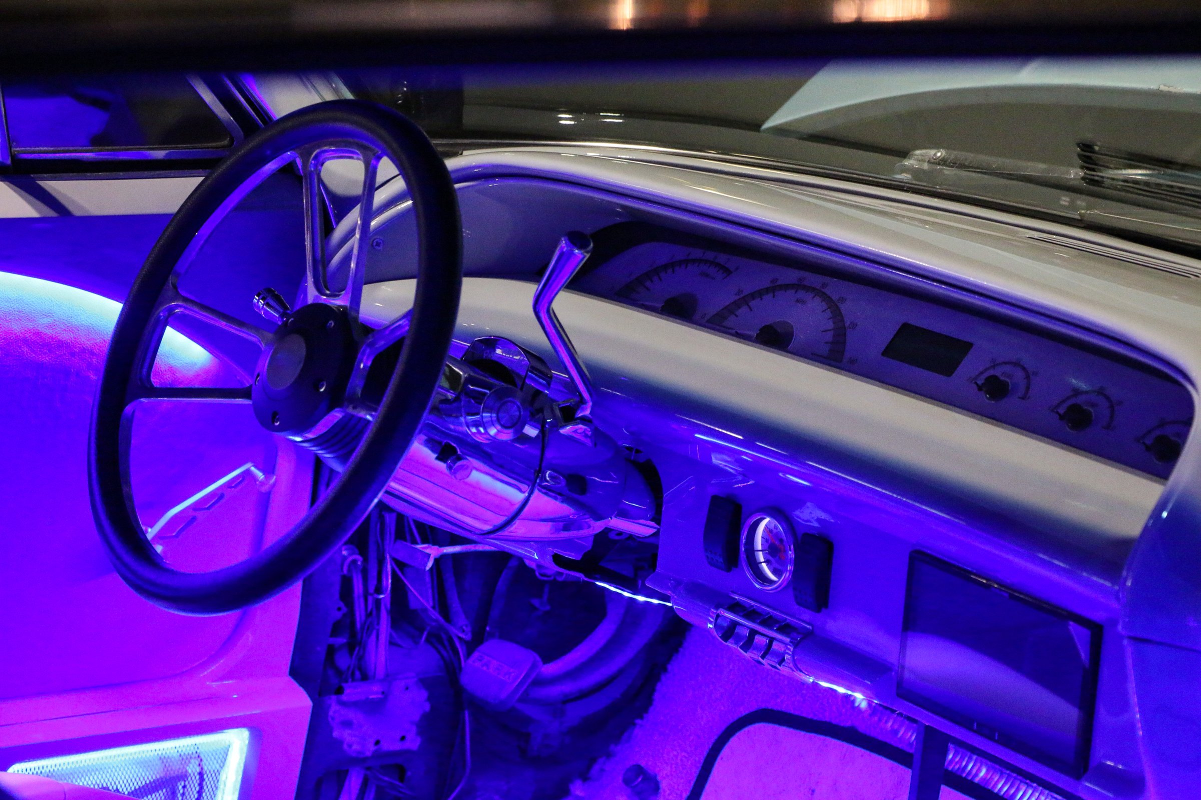A classic car decked out with purple lights