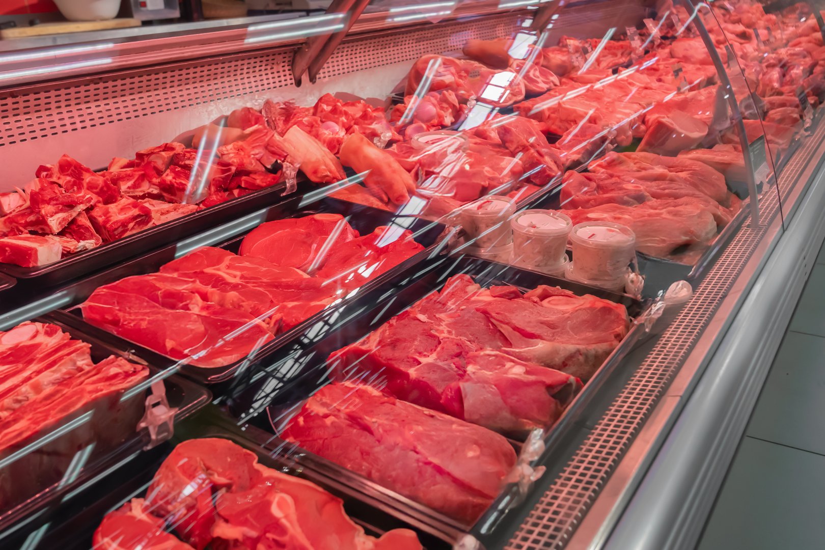 Fresh red meat display at a shop featuring beef and pork cuts in a well-organized showcase for customers during daylight hours. Chilled fresh meat, beef or pork fillet on a display case red lighting. High quality photo