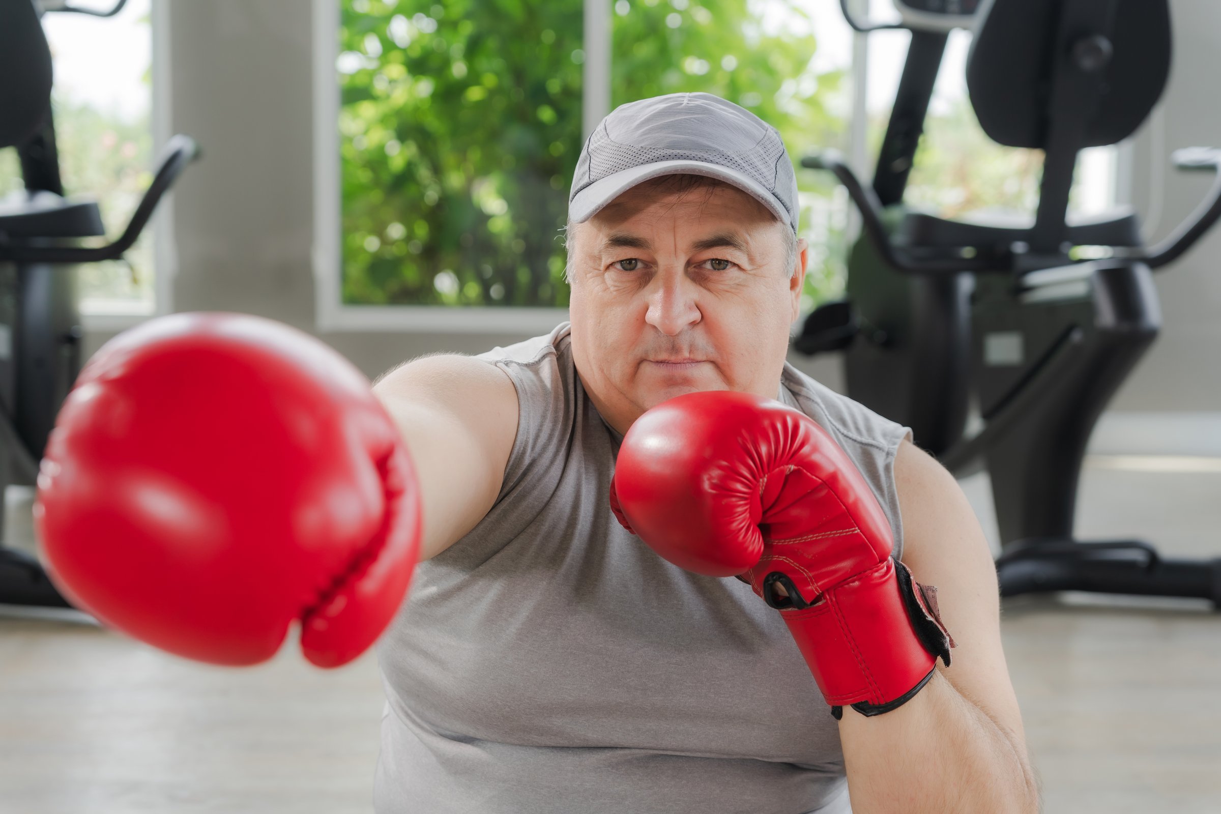 Fat man wearing boxing gloves working out in a gym