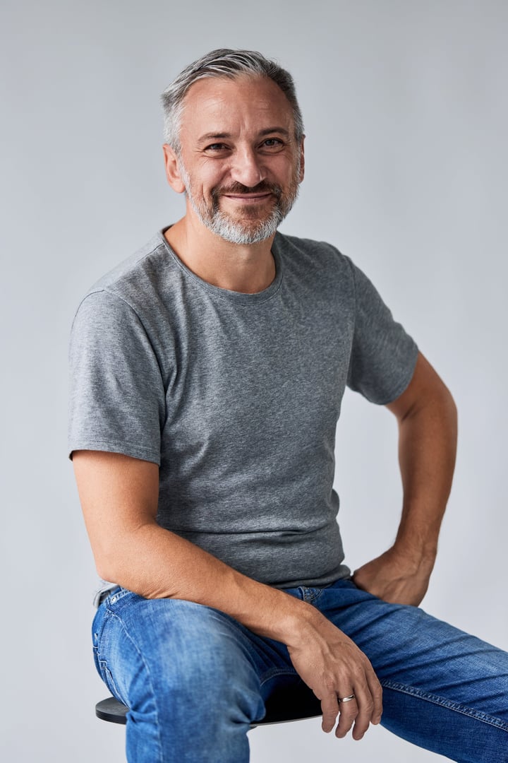 A smiling senior man, posing for the camera, sitting on the chair, smiling, isolated on the white background.
