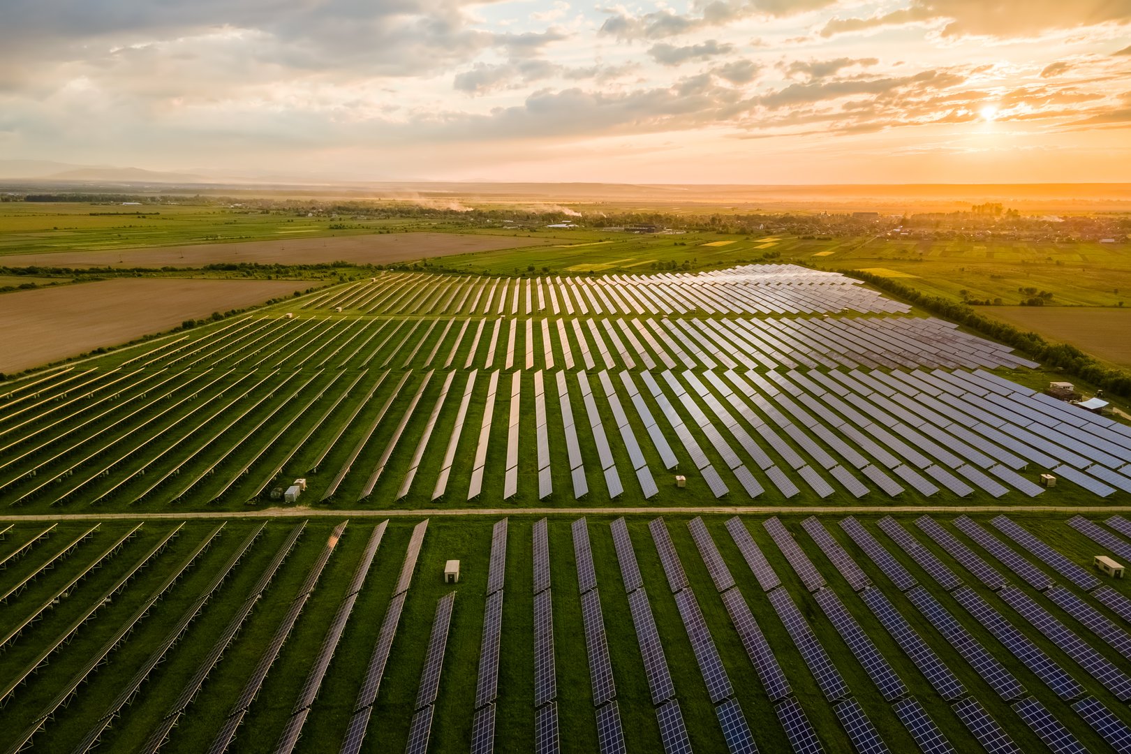 Aerial view of large sustainable electrical power plant with many rows of solar photovoltaic panels for clean ecological electric energy at sunrise. Renewable electricity with zero emission concept.