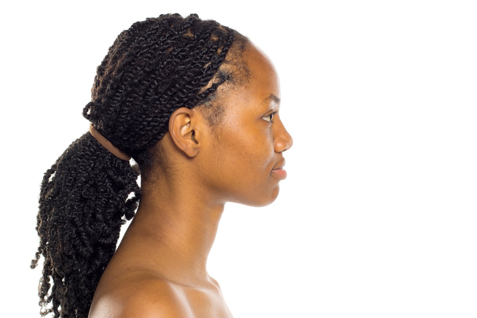 Black woman with braided ponytail in profile view, bare shoulders, studio shot on white background