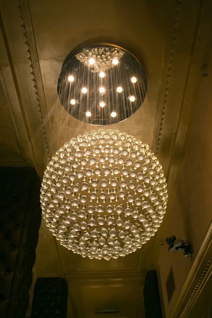 A spherical chandelier made of numerous small glass orbs hangs from the ceiling, casting a warm glow.
