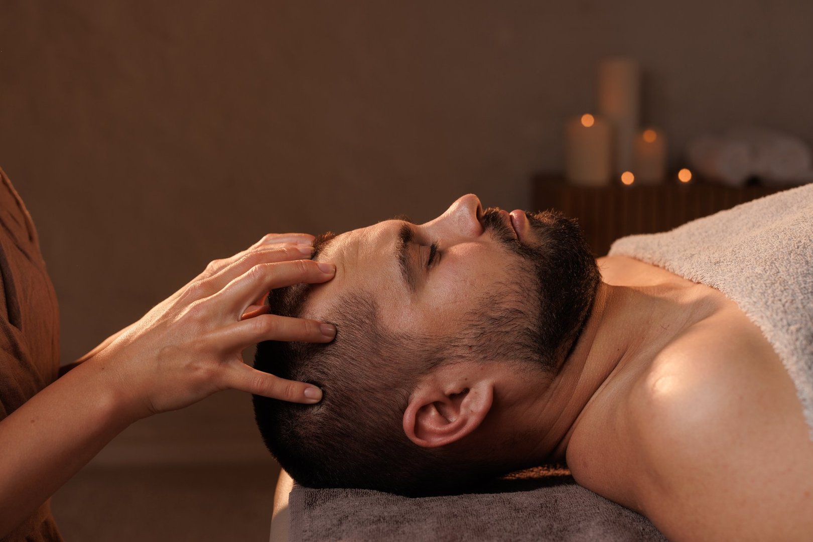 Young man receiving facial massage in beauty salon, closeup