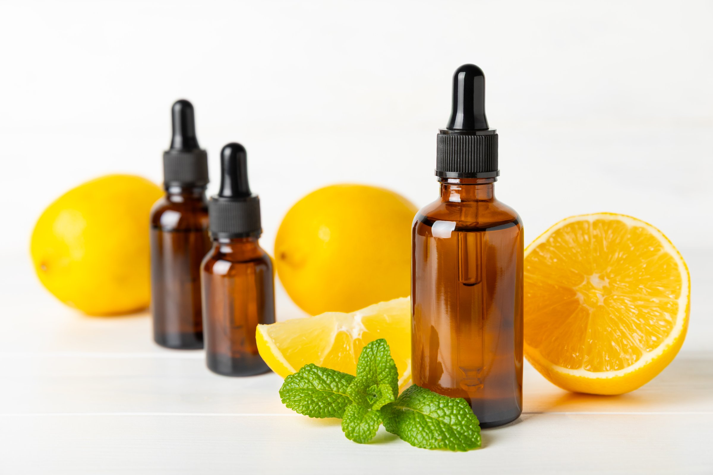 Lemon essential oil in a bottle with sliced lemon and leaves on a wooden background. Lemon oil. Perfume bottle with aromatic essential oil. Serum, lemon extract. Vitamin C. Natural cosmetics. Aromatherapy. Spa. Space for text.