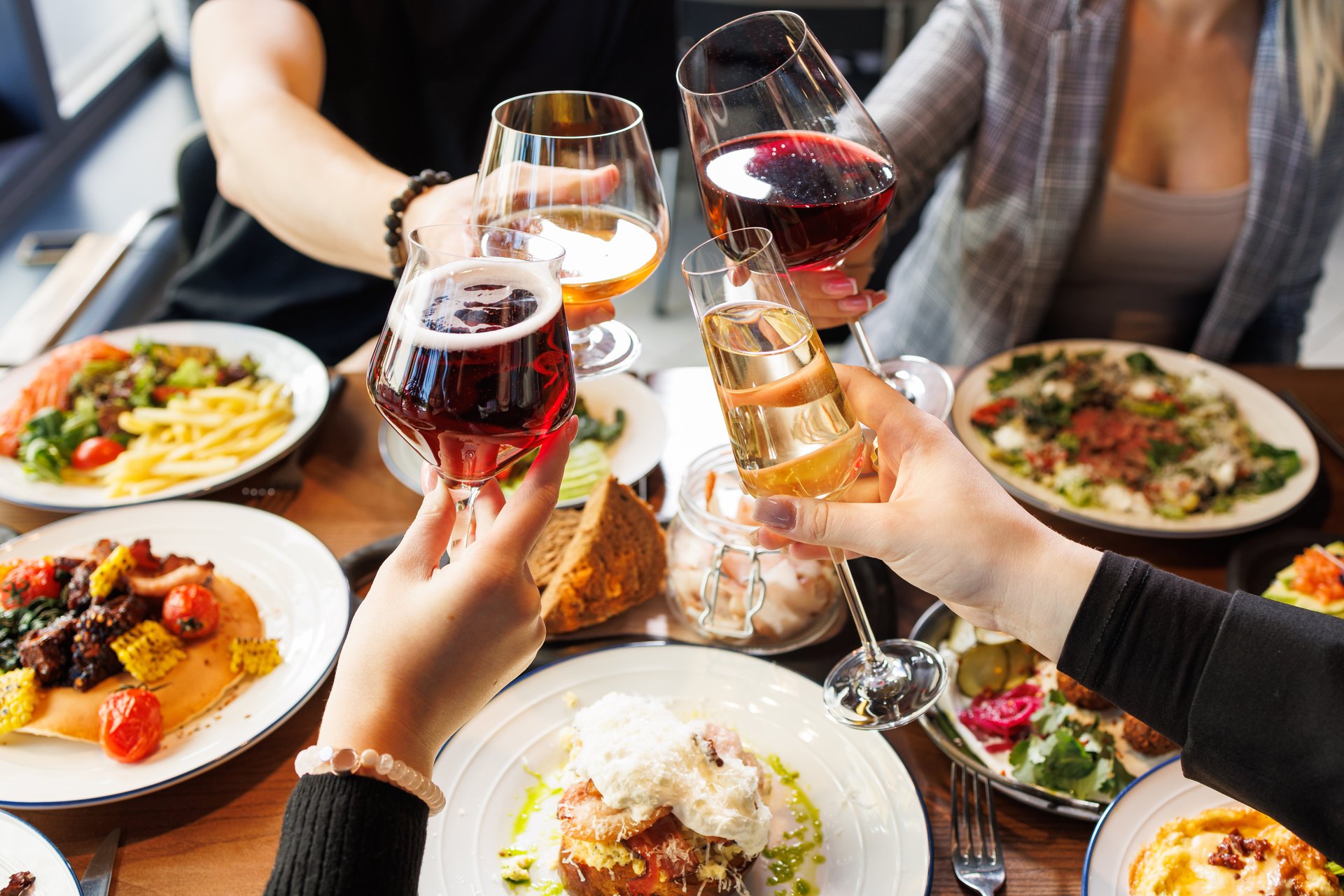People clinking glasses of red wine at served table, closeup