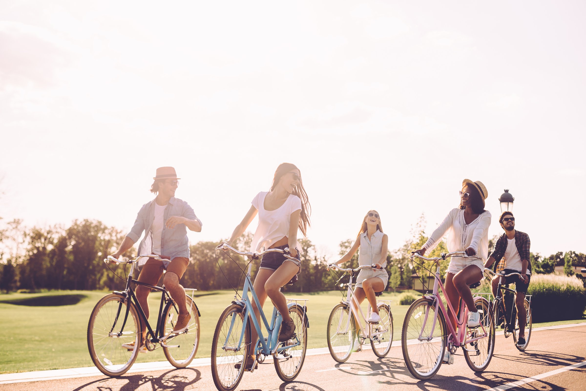 Group of young people riding bicycles along a road and looking happy