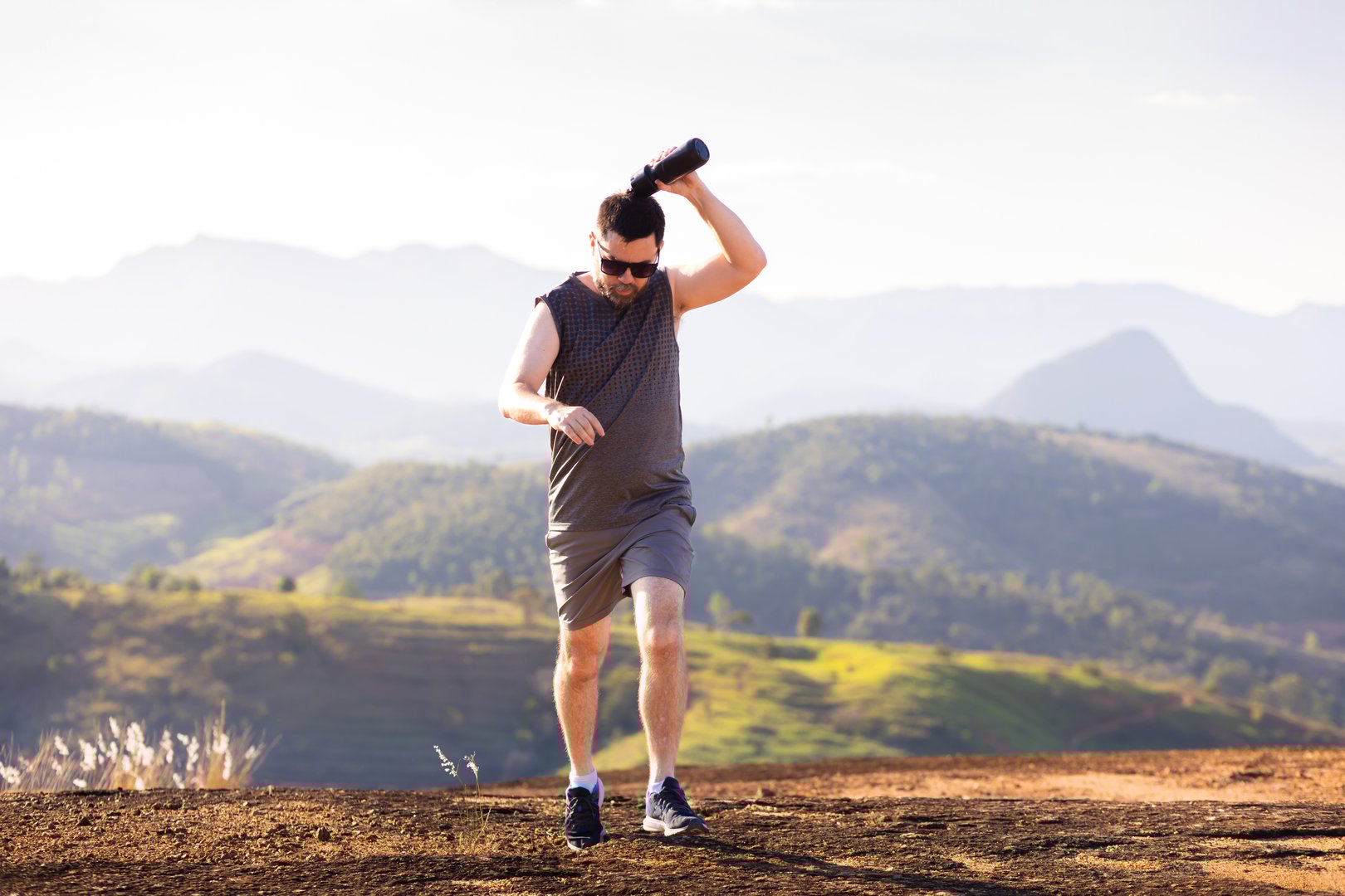 Brazilian athlete training outdoors, refreshing with water splash from a bottle while running. Active lifestyle and hydration concept