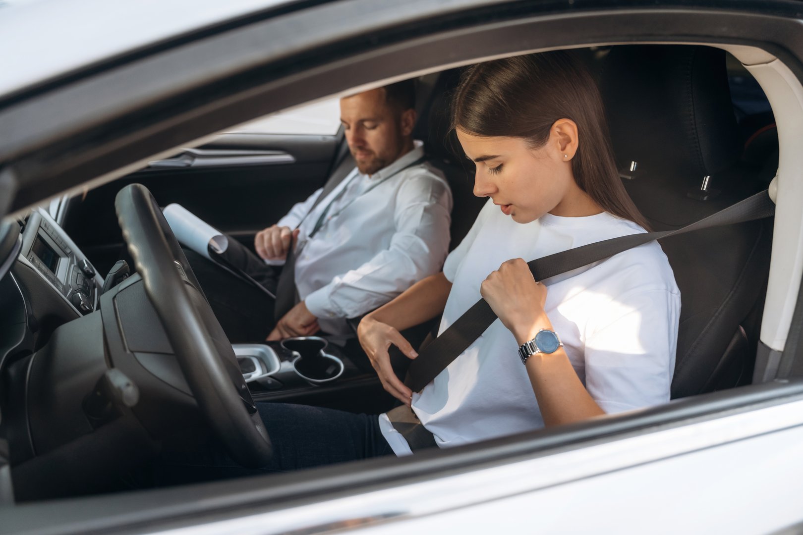 Wearing the safety belt. Woman is with instructor in car, driving school concept.