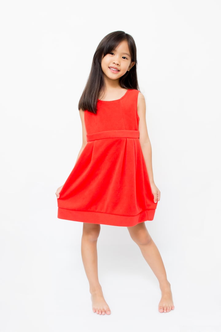 Smiling little Asian child in fashion red dress